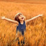 девочка раскинула руки в пшеничном поле