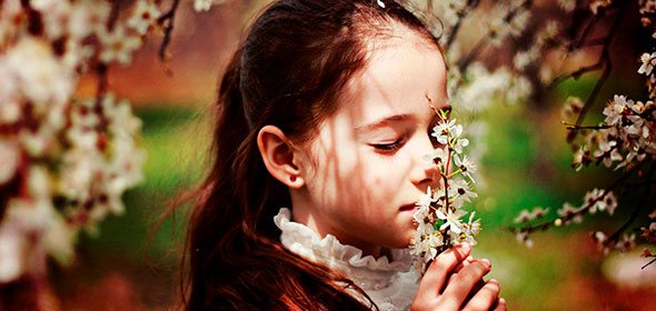 Девочка в поле нюхает цветы
