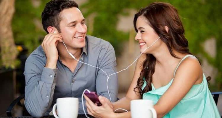 Девушка и парень вместе слушают музыку с телефона
