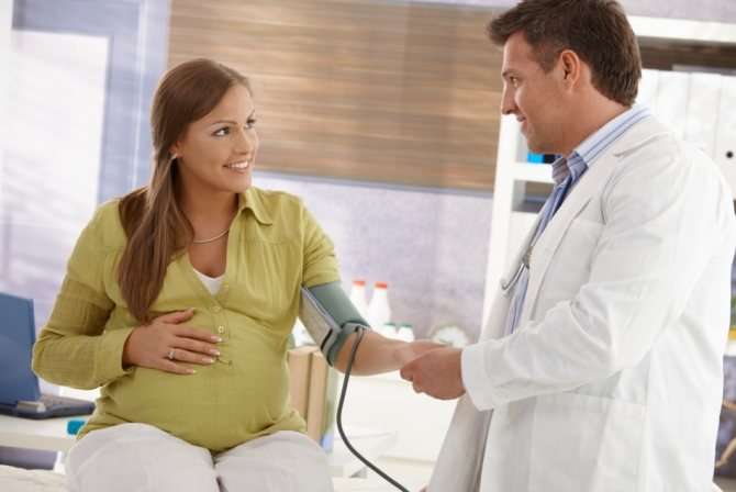 Доктор измеряет давление у беременной для понимания наличия гипертонии