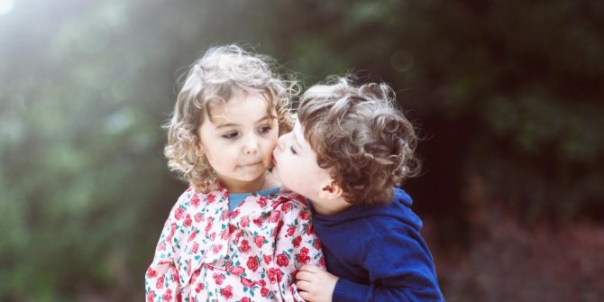 Мальчик целует девочку в щеку