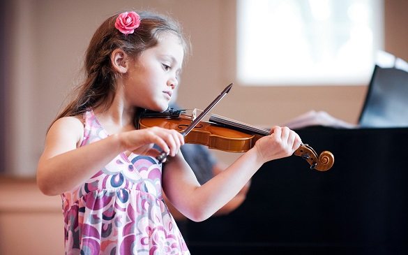 Маленькая девочка держит в руках скрипку