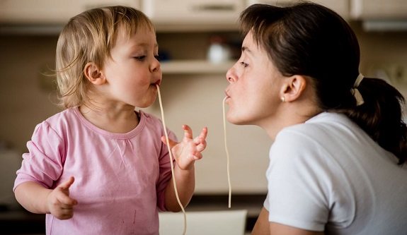 Маленькая девочка и взрослая женщина кушают спагетти