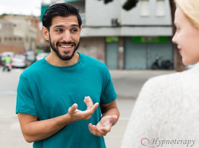 Молодой мужчина эмоционально жестикулируя руками говорит с девушкой.