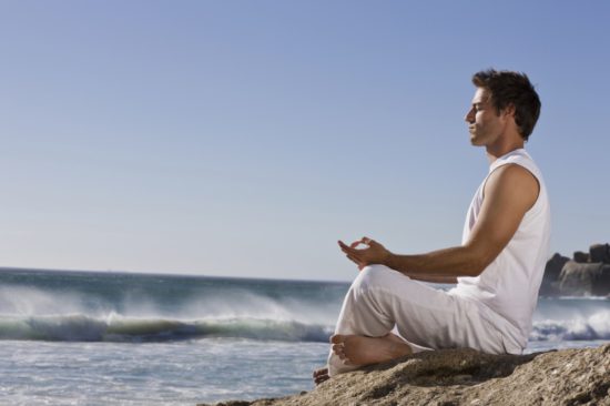 мужчина медитирует на берегу