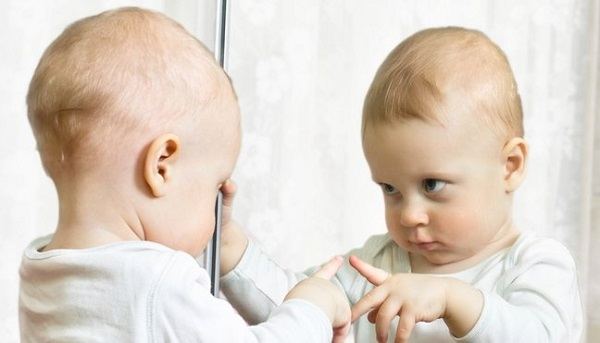 ребенок смотрит на свое отражение в зеркале