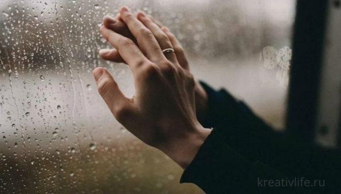 Руки мужчины и женщины на фоне дождя за окном