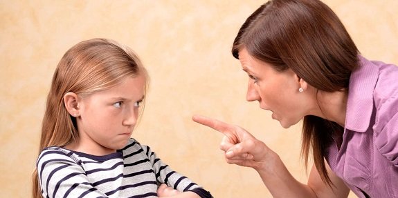 Взрослая женщина сердито смотрит на маленькую девочку и показывает на нее пальцем